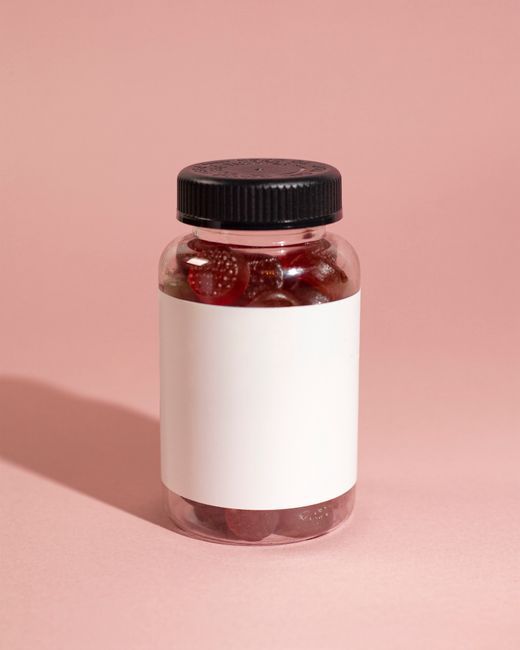 Clear bottle with red gummy vitamins on a pink background, emphasizing product simplicity.