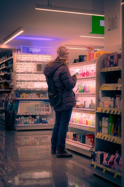 A woman browsing skincare products in a pharmacy in Belgrade.