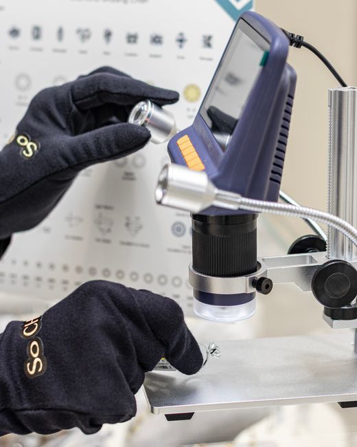 Detailed view of gemstone analysis using a digital microscope by gloved gemologist.