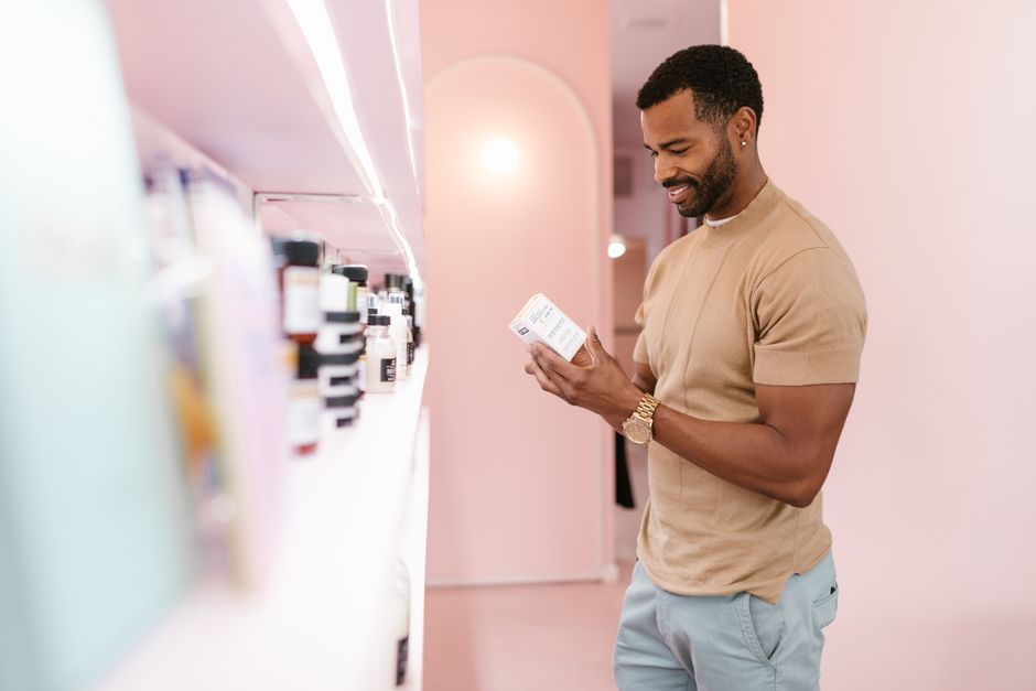 Man examines skincare product label in a modern, well-lit store.