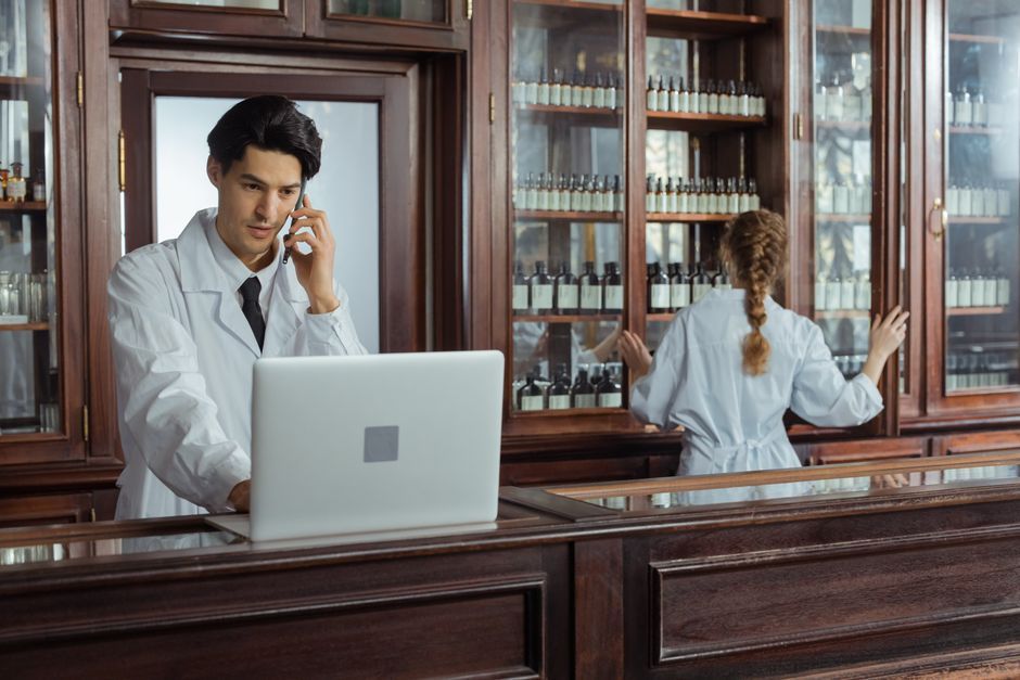 Pharmacists communicating and organizing medicines in a traditional pharmacy setting.
