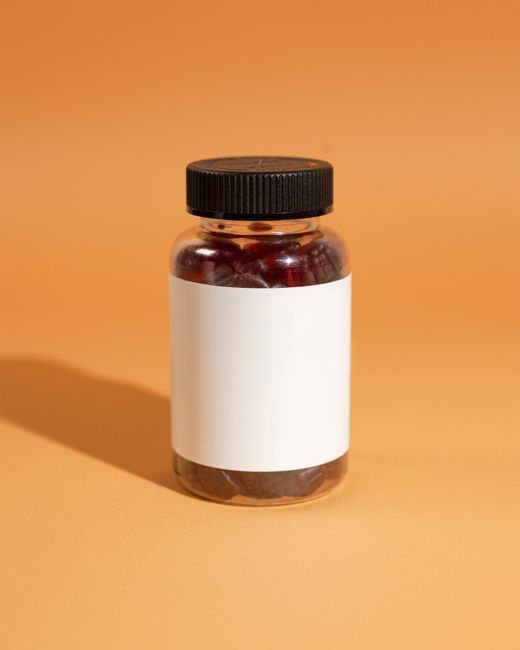 Clear bottle of gummies on vibrant orange surface, perfect for product promotions.