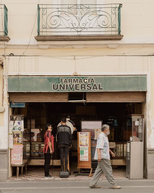 A vibrant street scene featuring Farmacia Universal in Puebla, Mexico with pedestrians.
