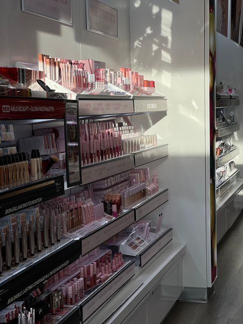 Brightly lit cosmetics aisle featuring a variety of makeup products neatly arranged on shelves.