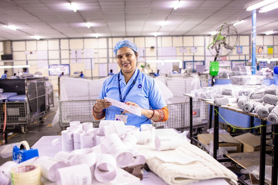 Female textile worker inspecting labels in a factory setting, showcasing blue-collar work environment.