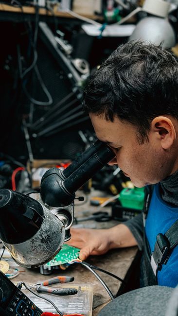 An engineer uses a microscope to inspect a circuit board for quality control.