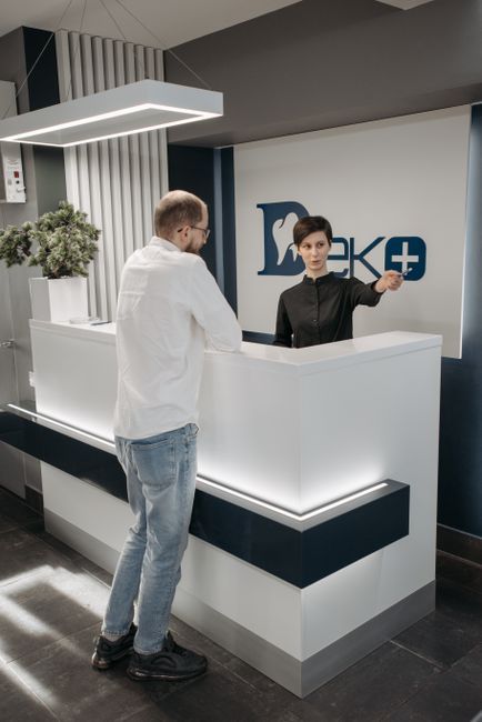 Modern dental clinic reception area with a receptionist assisting a patient.