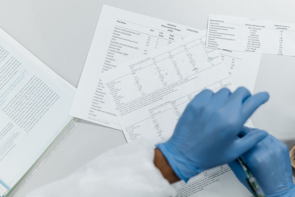 Close-up of gloved hands reviewing printed lab test results on a white surface.