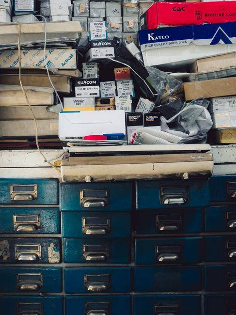 A cluttered vintage cabinet filled with assorted boxes and supplies in an indoor setting.